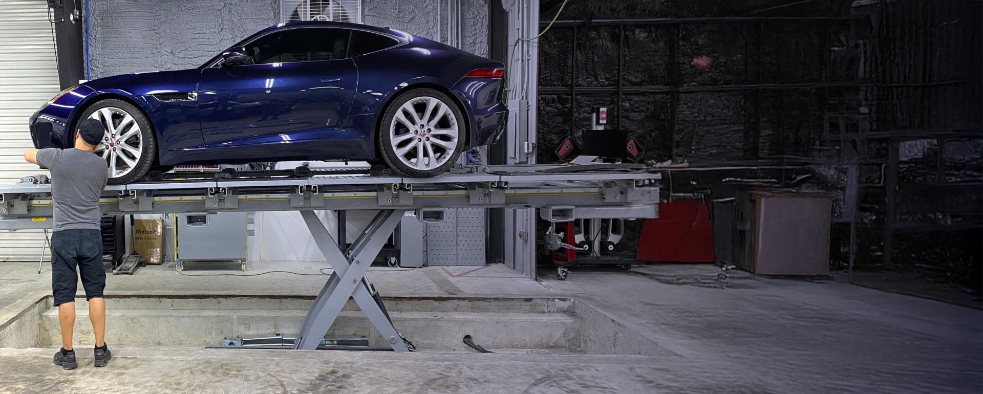A blue sedan being repaired in the Collision Center Orlando shop bay